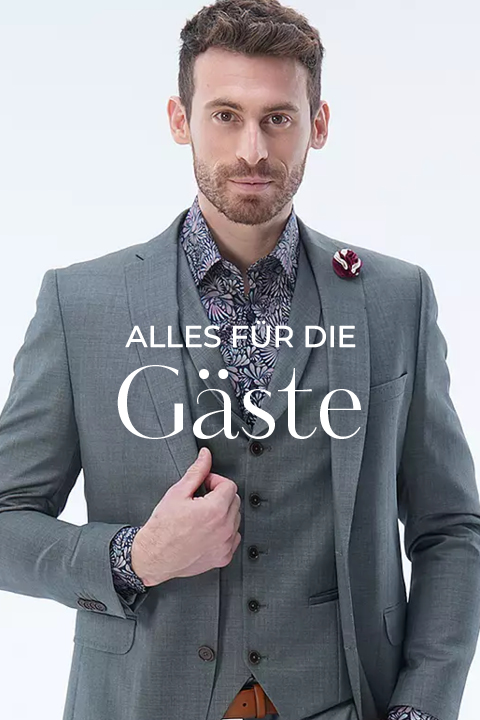 Ein Mann in einem grauen Anzug und gemustertem Hemd posiert selbstbewusst. Der überlagerte Text auf Deutsch lautet: "ALLES FÜR DIE GÄSTE.