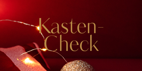 Eine festliche Szene mit dem Text „Kasten-Check“ in Gold auf tiefrotem Hintergrund. Warme Lichter und ein glitzerndes Goldornament sorgen für festliche Stimmung.