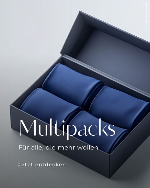 Eine Schachtel mit vier ordentlich gerollten blauen Krawatten. Der Text lautet: „Multipacks. Für alle, die mehr wollen. Jetzt entdecken.“ Die Schachtel ist geöffnet und zeigt die Krawatten auf einer grauen Oberfläche.