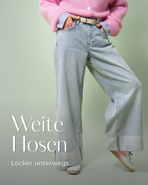 Eine Person trägt weite, hellblaue Jeans und einen rosa Pullover mit den Händen in den Taschen. Sie hat einen braunen Gürtel und trägt Turnschuhe. Der Text lautet „Weite Hosen“ und „Locker unterwegs“ auf Deutsch. Der Hintergrund ist hellgrün.