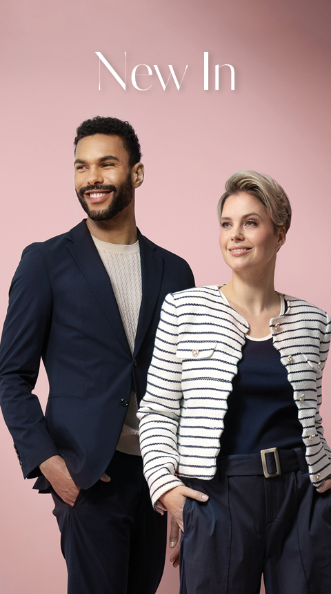 Ein Mann und eine Frau stehen vor einem rosa Hintergrund. Der Mann trägt einen marineblauen Blazer über einem beigen Hemd, während die Frau eine schwarz-weiß gestreifte Jacke trägt. Beide lächeln und blicken in die Ferne. Oben steht der Schriftzug „New In“.