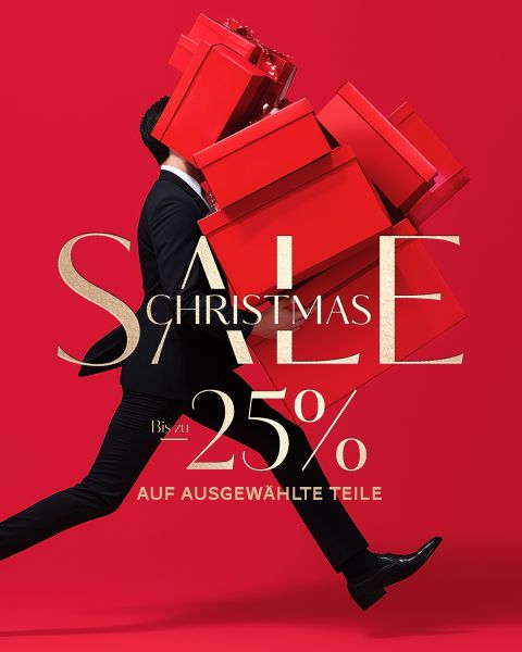 Ein Mann im Anzug trägt große rote Geschenkkartons mit der Aufschrift "Christmas SALE 25% auf ausgewählte Teile" auf rotem Hintergrund.