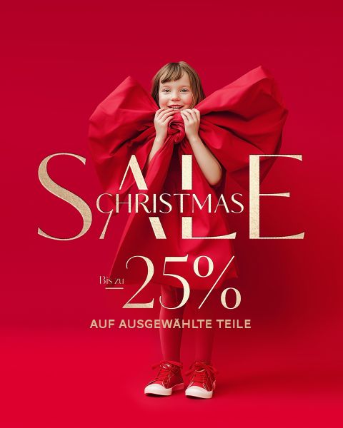 Lächelndes Kind, das eine riesige rote Schleife hält, vor rotem Hintergrund mit Text: "Christmas Sale, Bis zu 25% auf ausgewählte Teile.