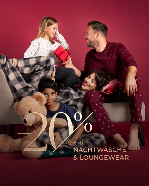 Eine lächelnde Familie im Schlafanzug sitzt zusammen mit einem Teddybär auf einer Couch und hält ein Geschenk in der Hand. Der Text lautet: "-20% auf Nachtwäsche & Loungewear.".