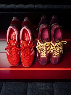 Zwei Paar adidas-Sneaker: eines in Rot mit weißen Streifen, das andere in Lila mit gelben Streifen, nebeneinander auf einer rot gestreiften Fläche.